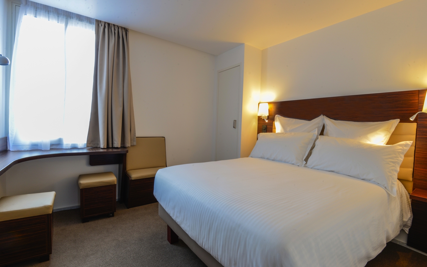 Doppelzimmer mit Bett, Schreibtisch und Fenster in einem Hotelzimmer.