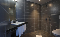 Modernes Badezimmer mit grauen Fliesen, Waschbecken und offener Dusche.