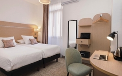 Modernes Hotelzimmer mit zwei Betten, Schreibtisch und Laptop.