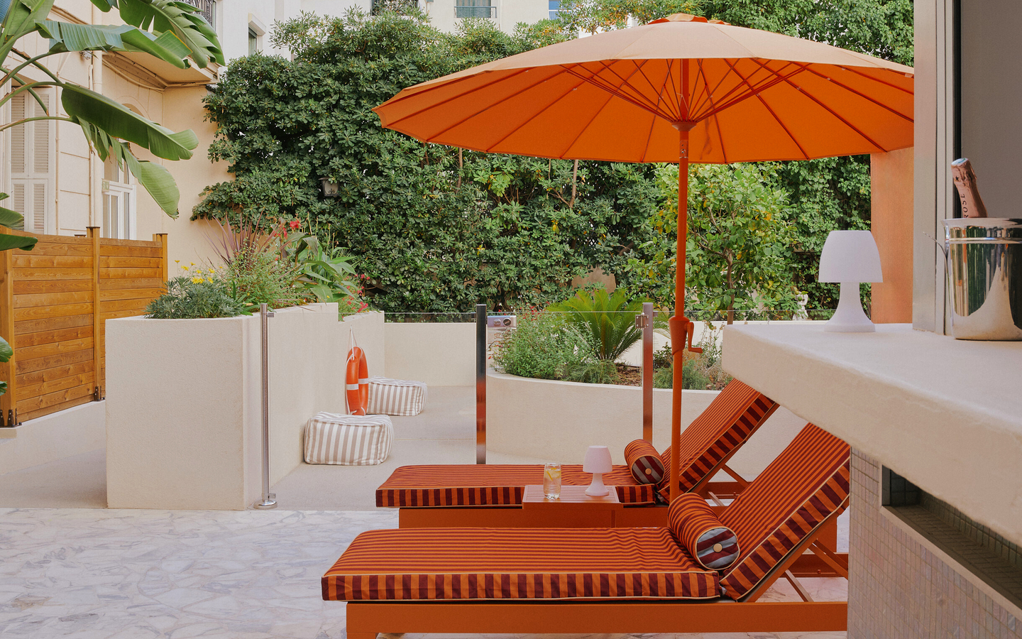 Zwei orange Liegestühle und Sonnenschirm auf Terrasse im Grünen