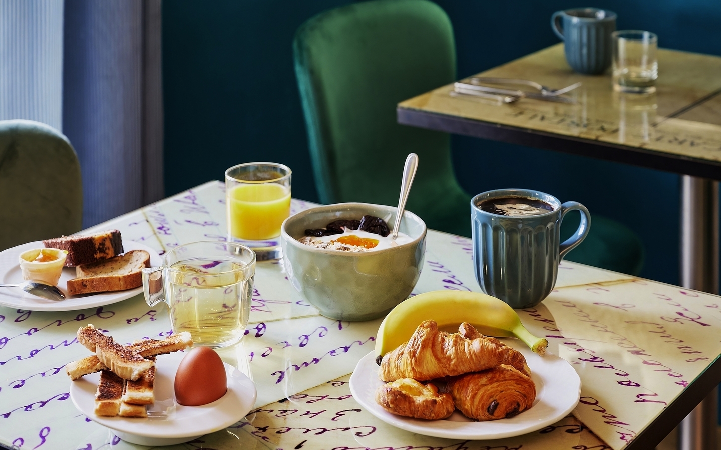 Frühstückstisch mit Croissants, Kaffee, Saft und Marmeladenbrot in einem Hotel.