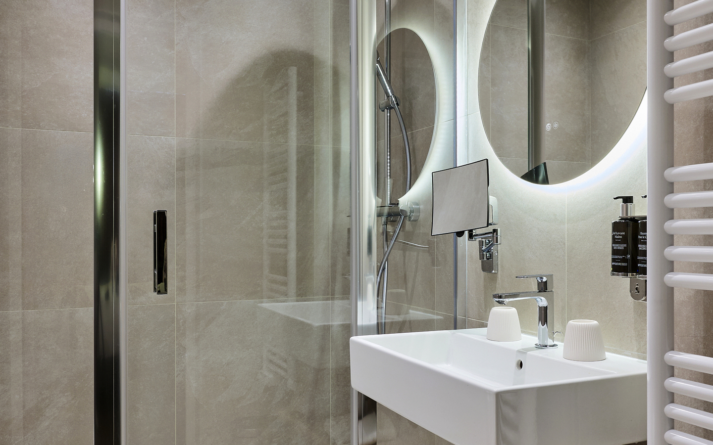 Modernes Hotelbad mit Dusche, Waschbecken und Handtuchhalter.