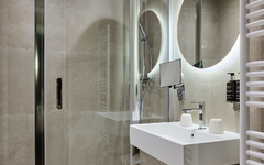 Modernes Hotelbad mit Dusche, Waschbecken und Handtuchhalter.