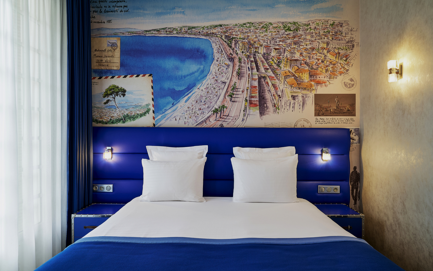 Hotelzimmer mit großem Bett, blauen Details und Wandbild von Côte d’Azur.