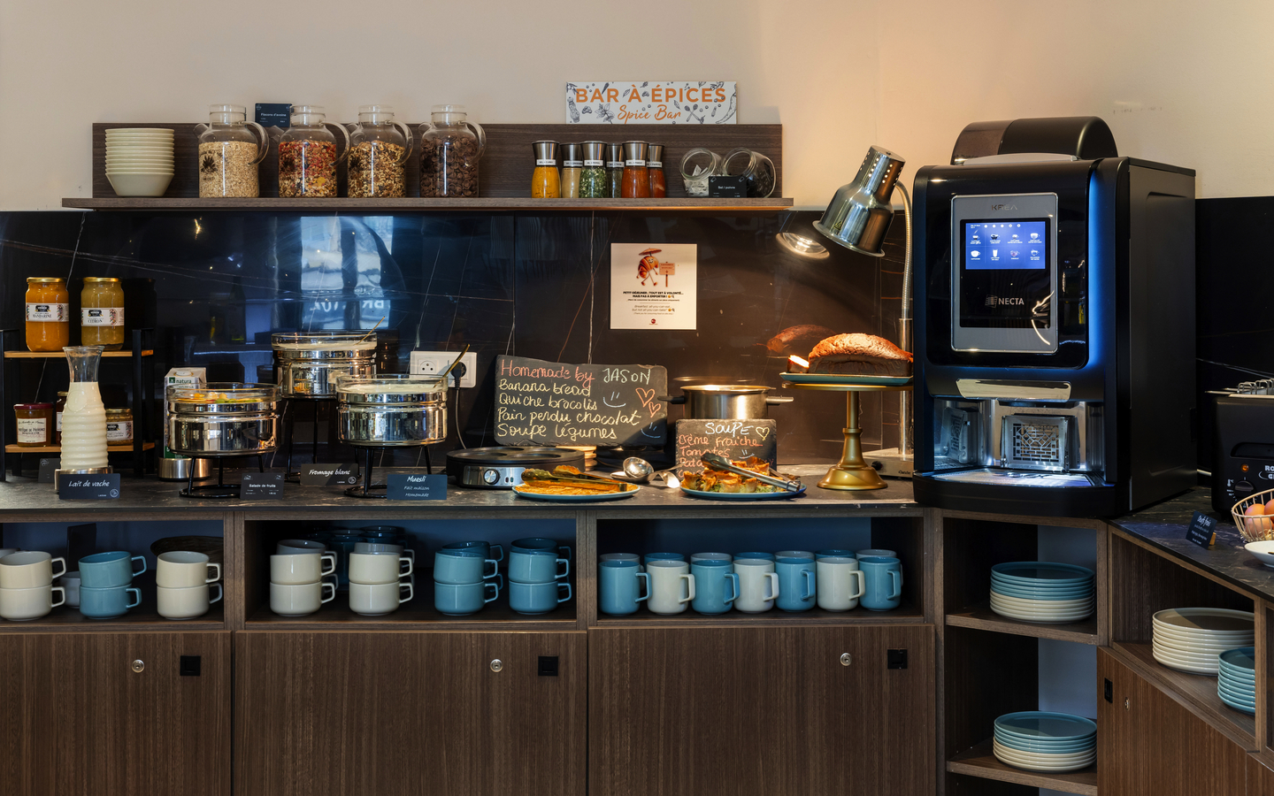 Frühstücksraum mit Buffet, Kaffeeautomat, Geschirr und Lebensmitteln im Hotel KHLA Cote d'Azur.