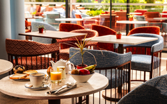 Tisch im Café mit Frühstück und Obst, helle Einrichtung, Blick auf Terrasse.