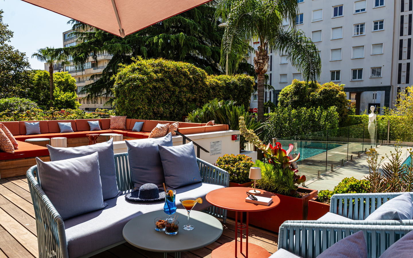 Terrasse des Hotels mit Sitzgelegenheiten, Pflanzen und einem Getränketisch.