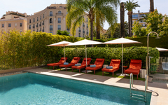 Poolbereich des Hôtel Le Canberra mit Liegen und Sonnenschirmen.