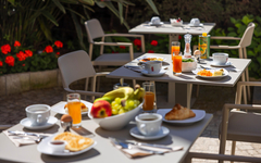 Frühstückstische im Freien mit Speisen und Getränken im Hotelgarten.
