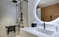 Modernes Hotelbad mit großer Dusche und beleuchtetem Spiegel.