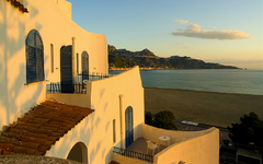 Hotel im mediterranen Stil mit Blick auf das Meer bei Sonnenuntergang.