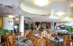Restaurant im Hotel Sporting Baia mit gedeckten Tischen und Holzstühlen.