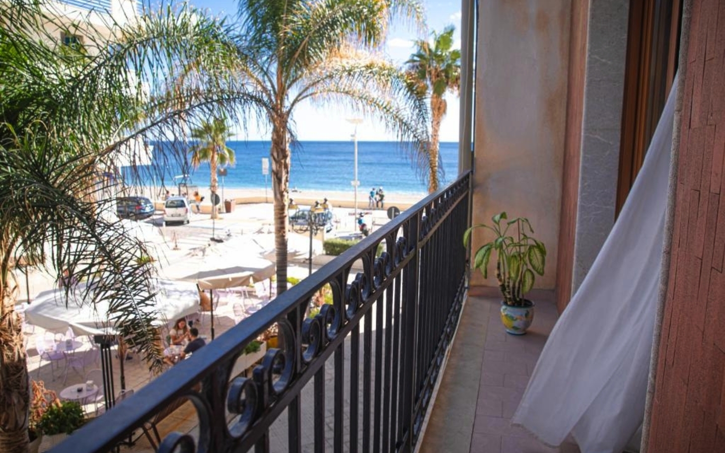 Blick vom Balkon mit Meer und Palmen in Letojanni, Italien.