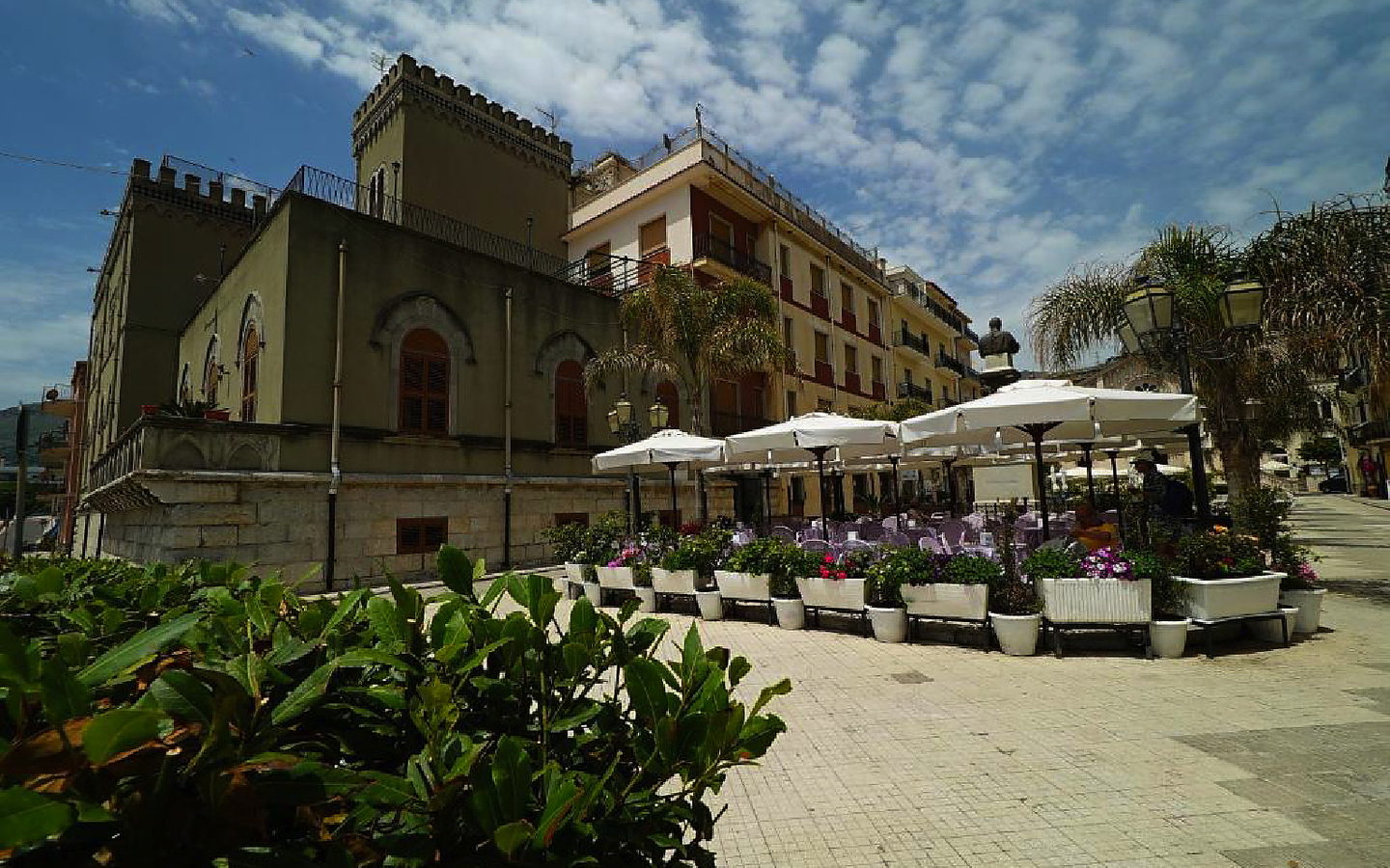 Historisches Gebäude mit Terrasse und Sonnenschirmen in Letojanni, Sizilien.