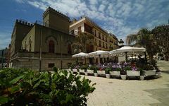 Historisches Gebäude mit Terrasse und Sonnenschirmen in Letojanni, Sizilien.
