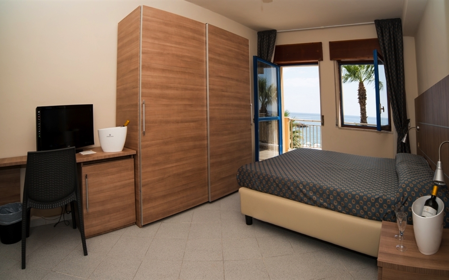 Hotelzimmer mit Meerblick, Bett, Schreibtisch und Schrank in Sizilien.