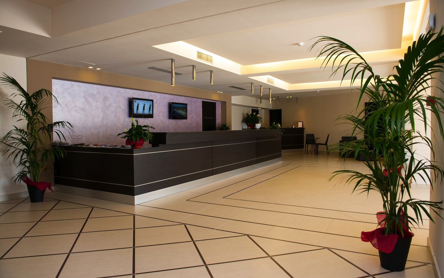 Hotel-Lobby mit moderner Rezeption und grünen Pflanzen.