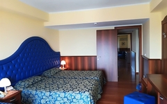 Hotelzimmer mit zwei Betten und blauer Polsterung in Sizilien.