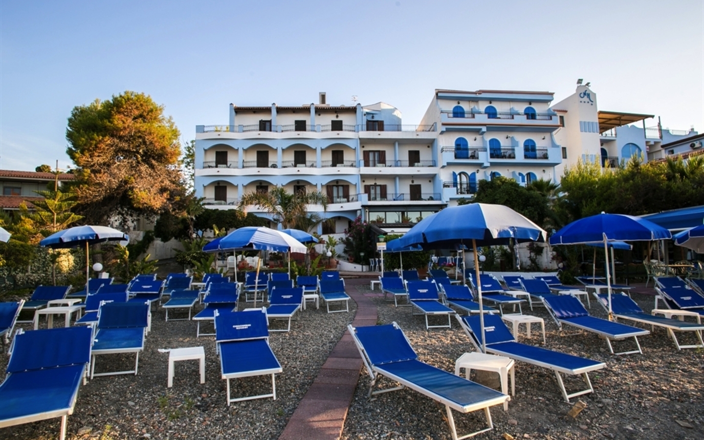 Sonnenschirme und Liegestühle vor einem Hotel am Strand in Giardini Naxos, Sizilien.