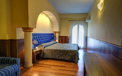 Hotelzimmer in Sizilien mit Doppelbett und Balkon, warmes Licht und Holzboden.