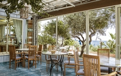 Terrasse eines Restaurants mit Holztischen und Blick auf das Meer