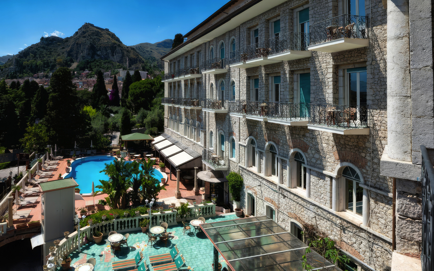 Außenansicht des Taormina Park Hotels mit Pool und Berglandschaft im Hintergrund.