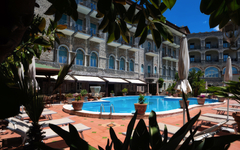 Hotelpool mit umliegenden Sonnenliegen und Gebäude im Hintergrund
