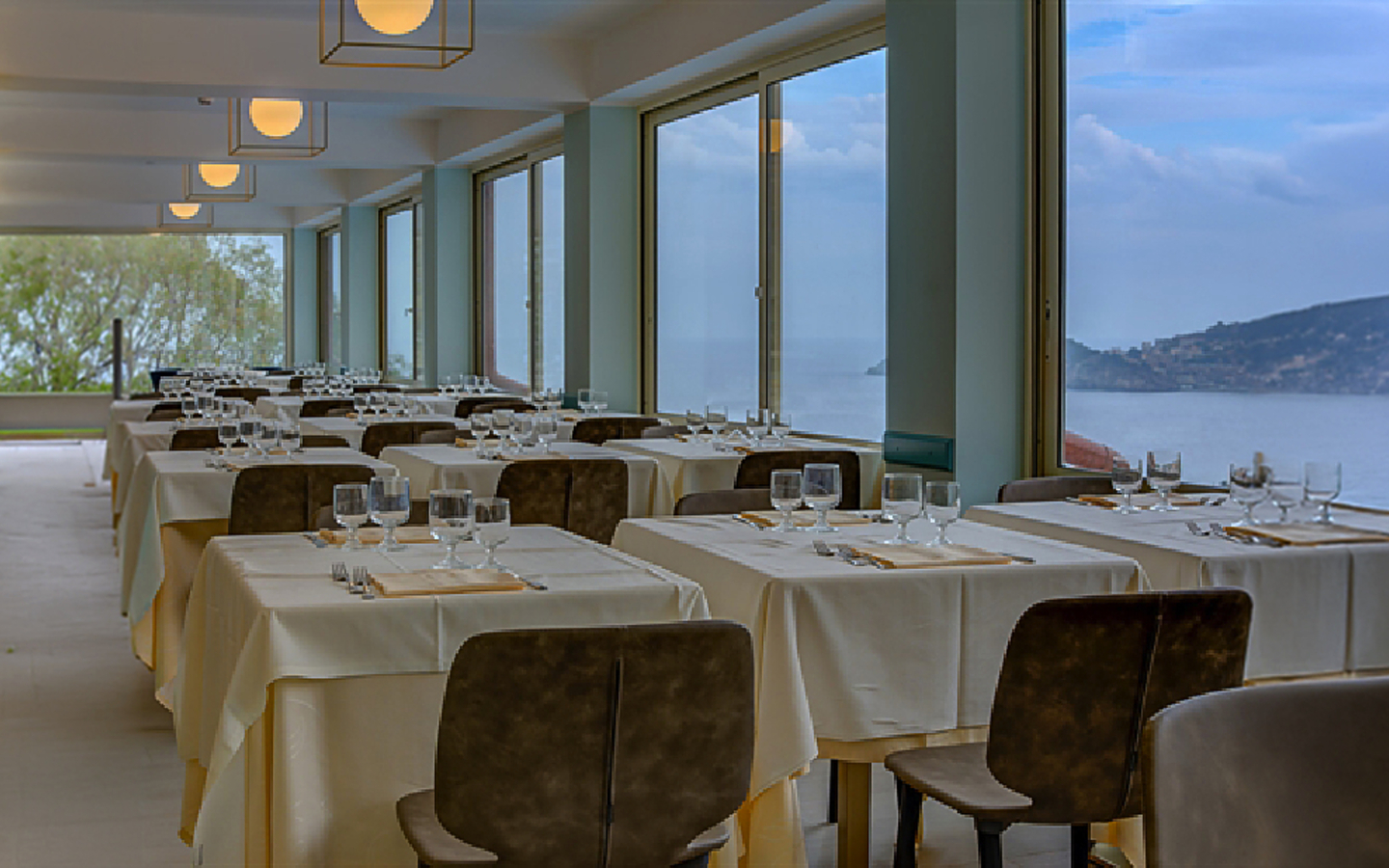Hotelrestaurant mit gedeckten Tischen und Meerblick.