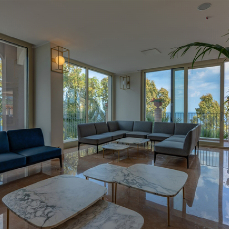 Hotel-Lounge mit Sofas, Marmortischen und Blick auf das Meer in Sizilien.