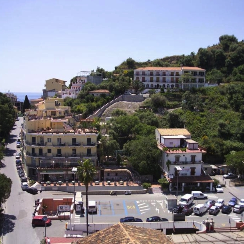 Straßenansicht mit Gebäuden und Hügeln in Taormina, Sizilien.