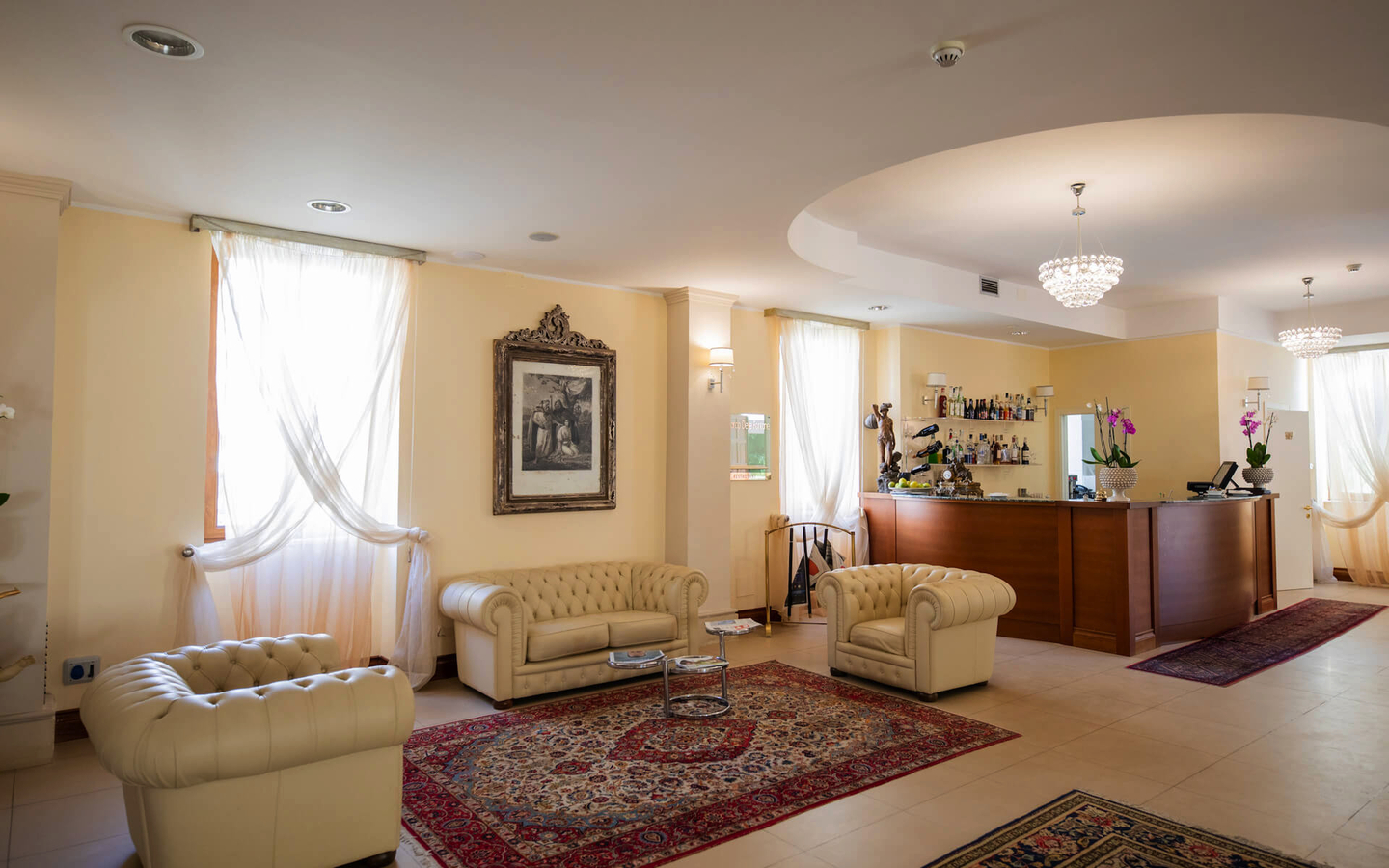 Hotellobby mit eleganten, beigen Ledersofas und einer Bar im Hintergrund.