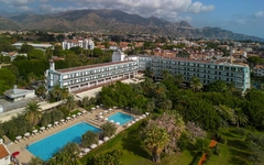 Hotel mit Pool und Garten aus der Luft, Berge im Hintergrund.