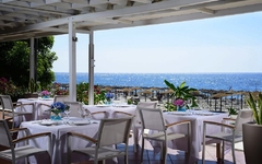 Restaurantterrasse mit Meerblick und gedeckten Tischen im Freien.
