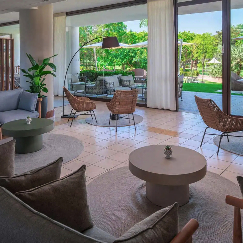Moderne Hotel-Lounge mit Blick auf einen grünen Garten.