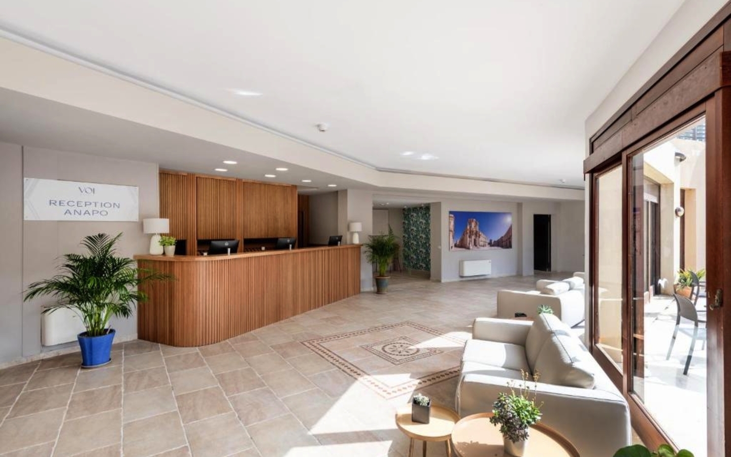 Heller Empfangsbereich des Voi Arenella Resorts mit Pflanzen und Sitzbereich.