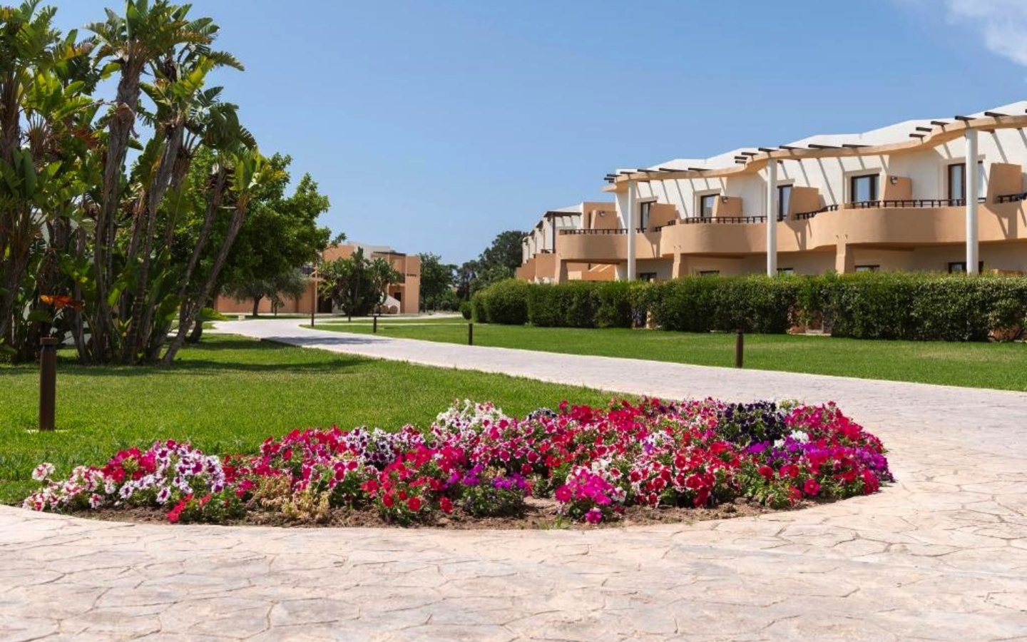 Gartenanlage mit blühenden Blumen vor einem Resort-Gebäude.