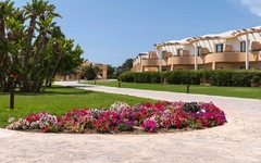 Gartenanlage mit blühenden Blumen vor einem Resort-Gebäude.