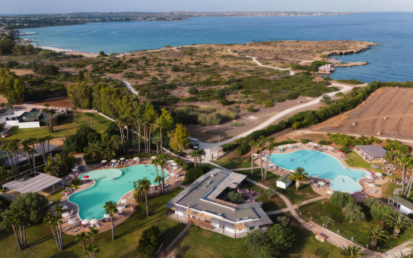 Luftaufnahme eines Resorts in Sizilien mit Pools und Blick auf das Meer.