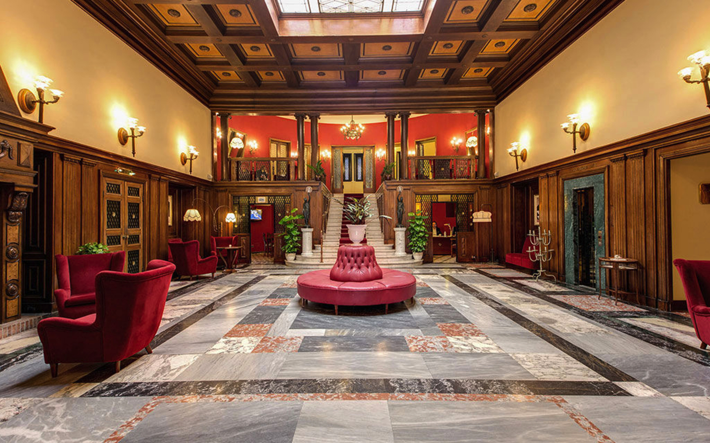 Großer eleganter Hotel-Lobbybereich mit Marmorboden und roten Sesseln.
