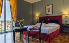 Elegantes Hotelzimmer mit Doppelbett, rotem Kopfteil und Tisch mit Stühlen.