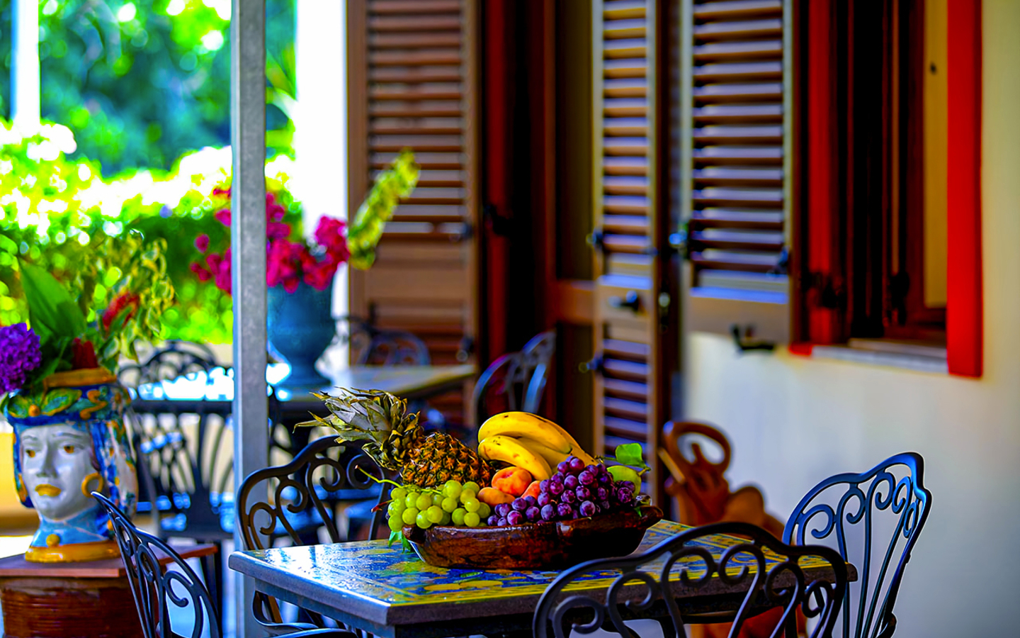Bunt dekorierte Terrasse eines Hotels mit Früchten auf einem Tisch.