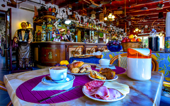 Frühstückstisch in einem gemütlichen Hotelrestaurant mit Aufschnitt und Gebäck.