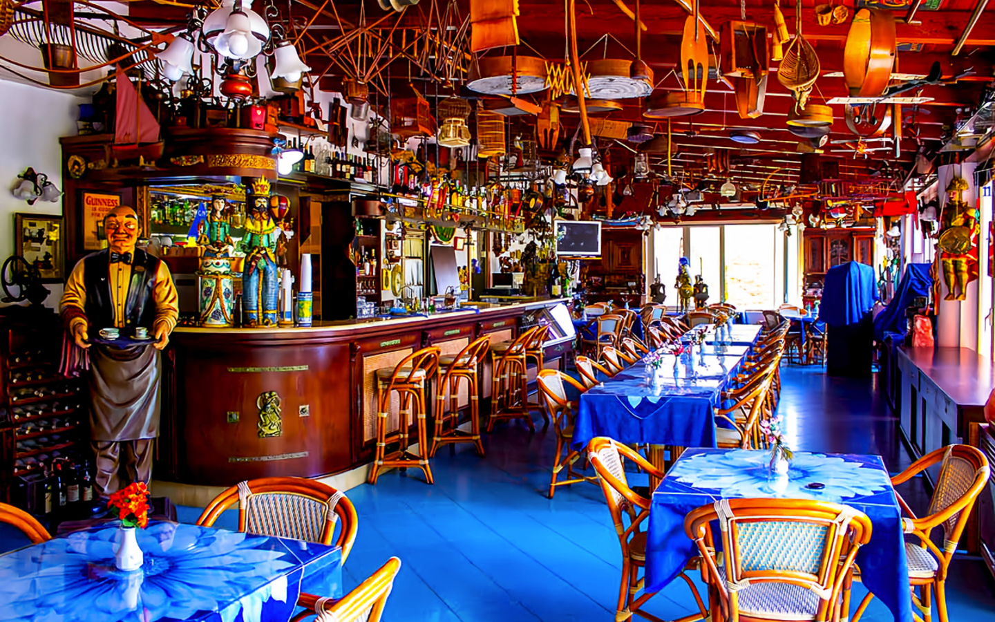 Bunt eingerichtetes Restaurant mit Bar und blauen Tischdecken.