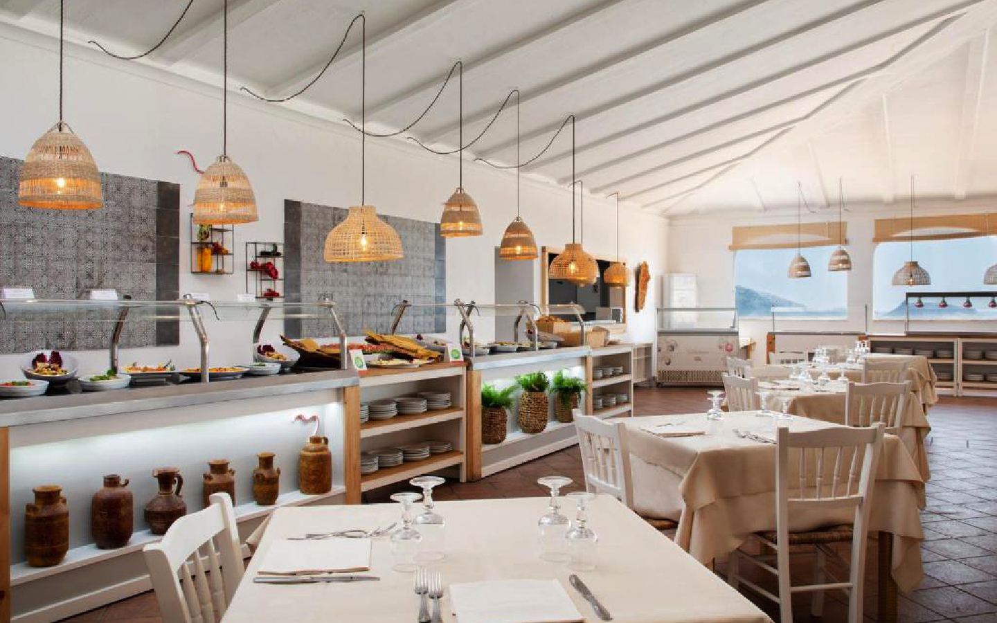 Helles Restaurant mit gedeckten Tischen und Buffet im Hintergrund.