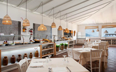 Helles Restaurant mit gedeckten Tischen und Buffet im Hintergrund.