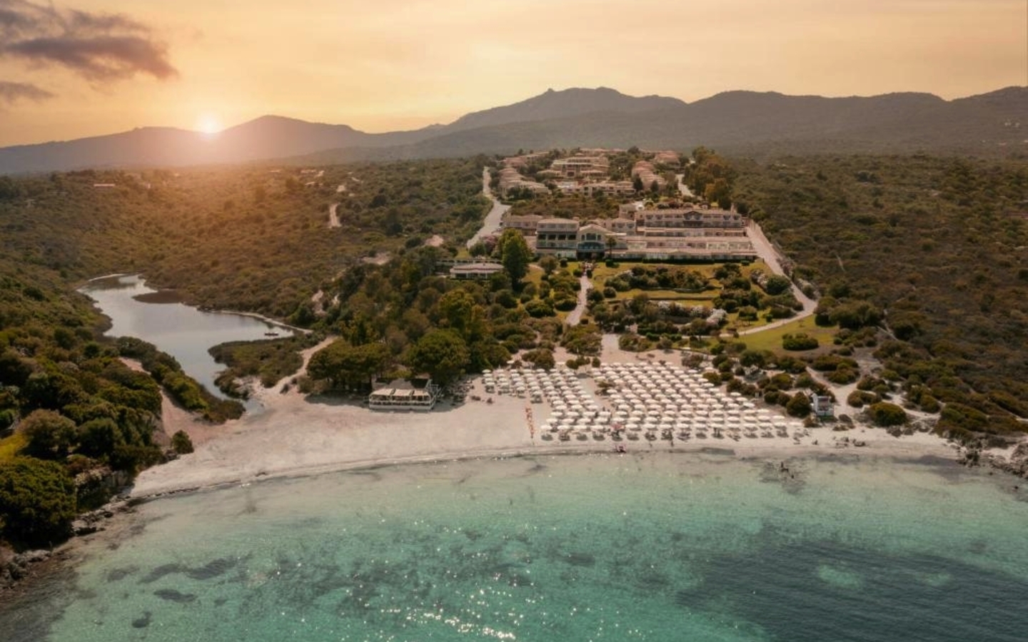 Luftaufnahme eines Hotels am Strand von Sardinien bei Sonnenuntergang.