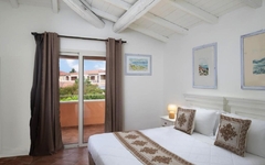 Hotelzimmer mit Doppelbett, weißer Decke und Zugang zu einem Balkon mit Ausblick.