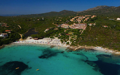 Luftaufnahme einer Hotelanlage in Sardinien, umgeben von grüner Landschaft und Küste.