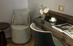 Hotelzimmer-Ecke mit Sessel, Tisch, Vase und Zeitschriften.