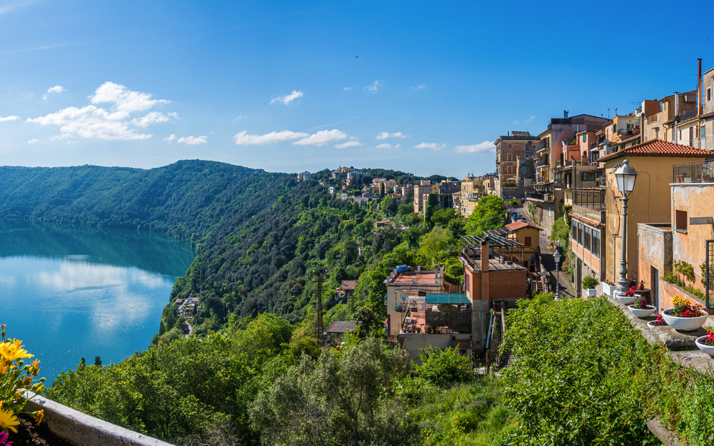 Blick auf eine italienische Stadt an einem See mit blühenden Pflanzen und klarem Himmel